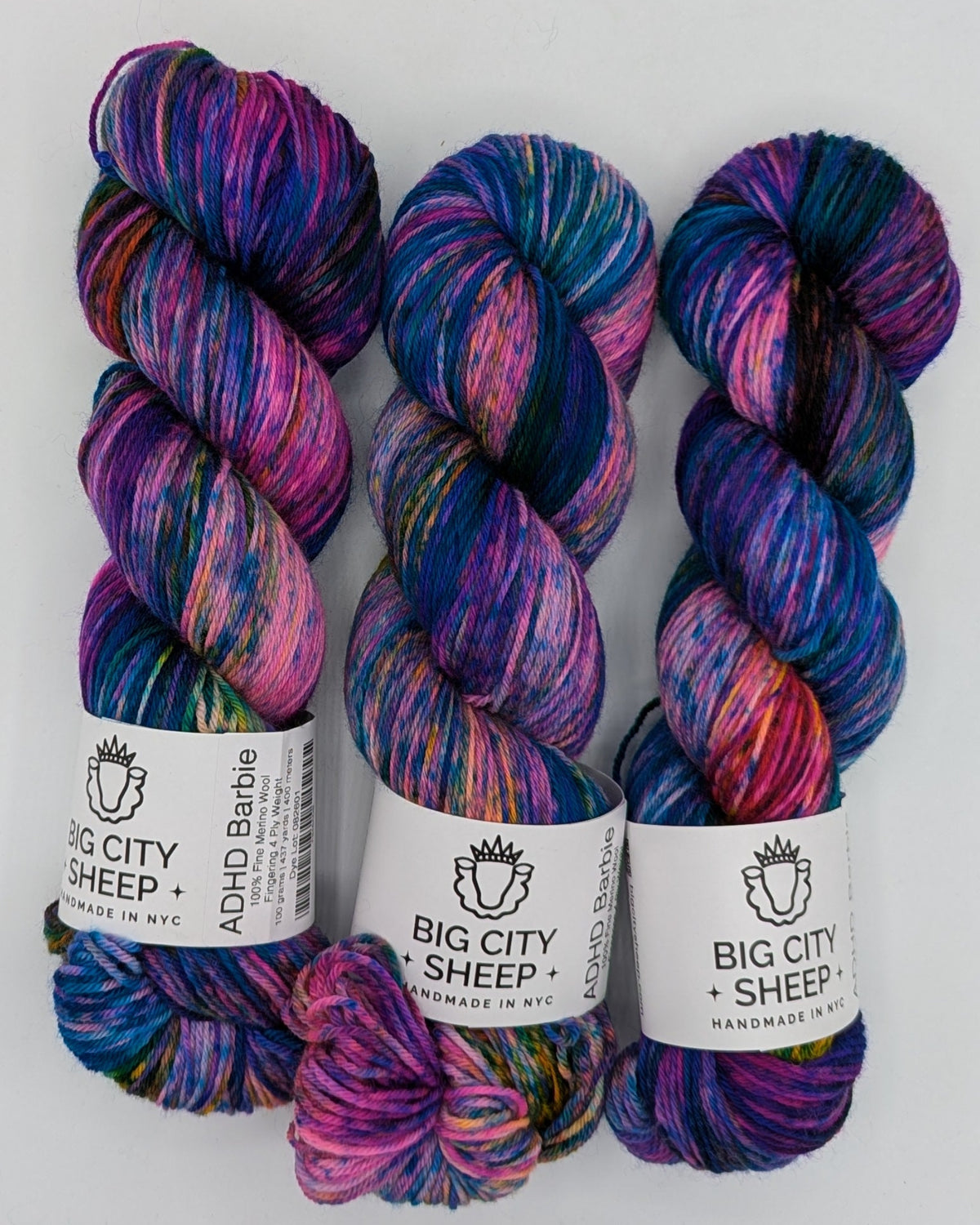 Three skeins of variegated yarn with white paper bands labeled 'Big City Sheep' arranged on a white surface.
