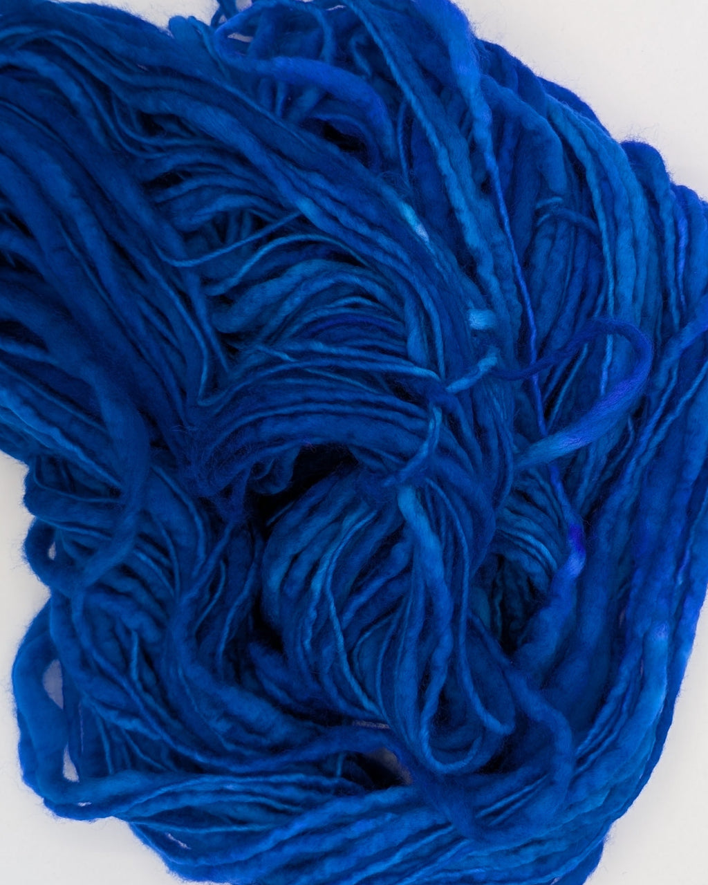 A swirl of vibrant royal blue yarn or thread on a plain white background.