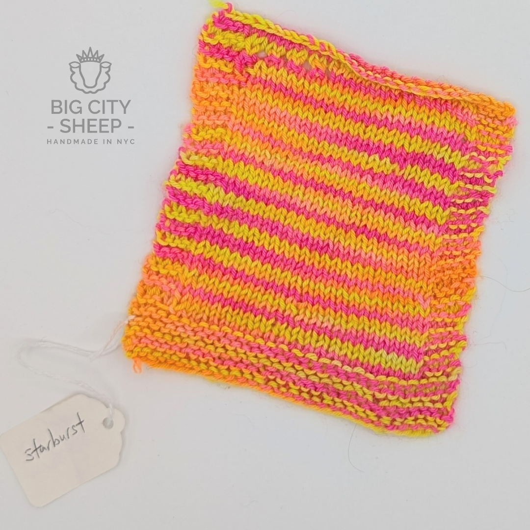 A square knitted wool swatch with horizontal stripes of neon pink, orange, and yellow, displayed on a white background with a 'Big City Sheep' logo and a 'starburst' tag.